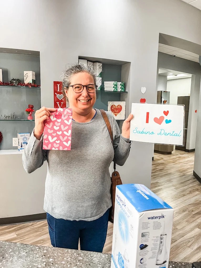 A patient holding an I love Sabino Dental sign